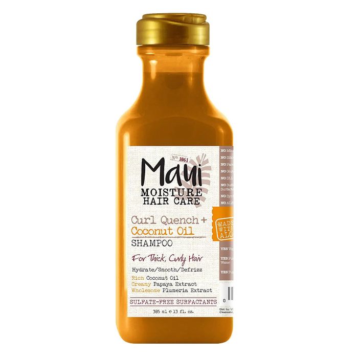 A bottle of orange and gold shampoo placed on a white backdrop.