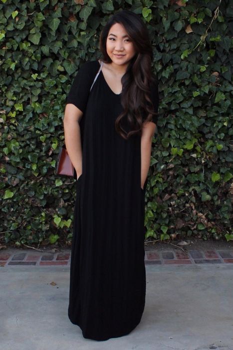 a reviewer dressed in the short sleeve black maxi dress with their hands casually tucked into the pockets