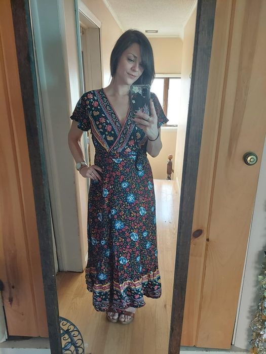 A reviewer in a navy printed maxi dress, striking a pose in front of a mirror