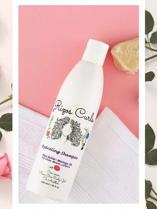 White shampoo bottle with a sketch of a face and curly hair, placed on a white towel next to smooth shampoo texture.