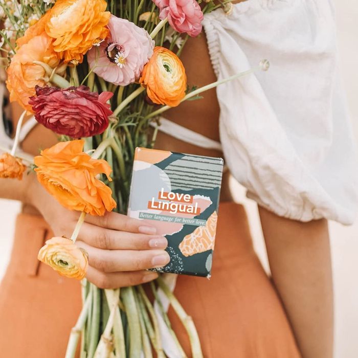 Person holding the love language card game with a bouquet of flowers
