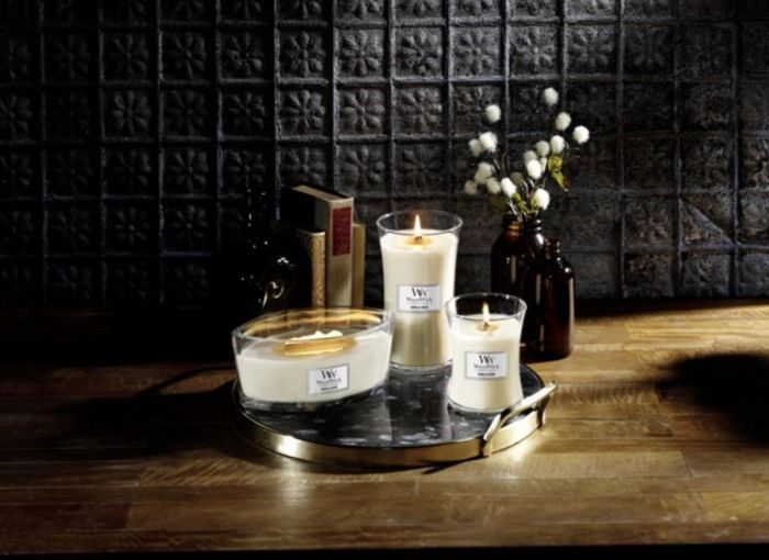 Three different sizes of the candle glowing softly on a vanity tray.