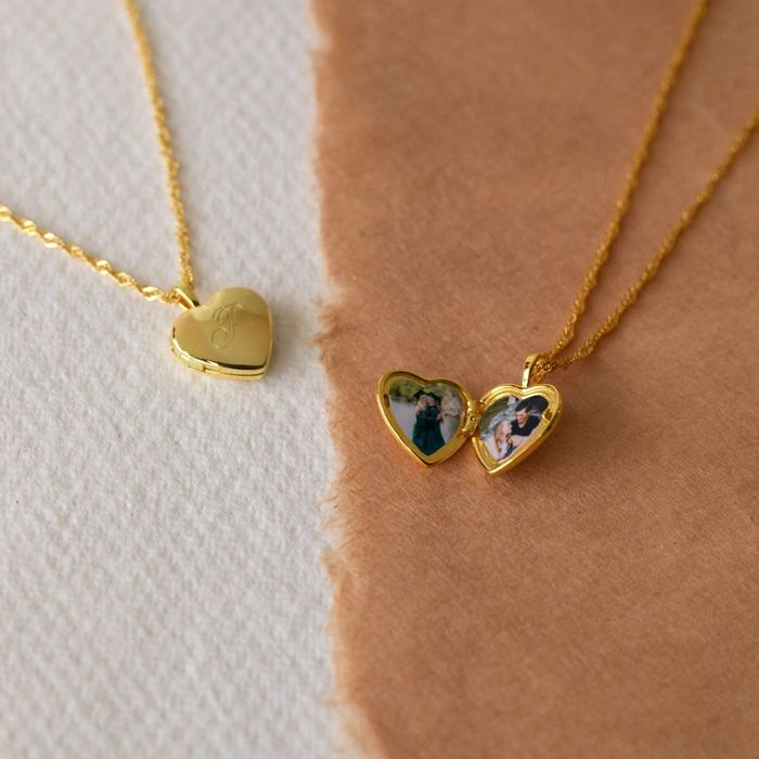 two gold heart-shaped lockets. The left locket is closed, and the right locket is open, showcasing two small photos inside
