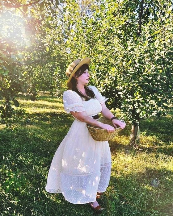 A reviewer sporting the white ruffled dress in a field