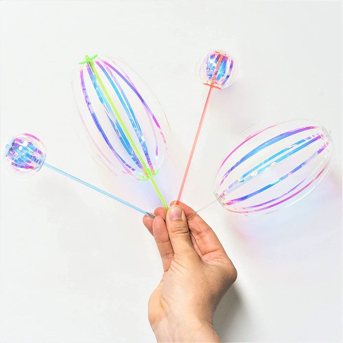 The twirling sticks, with shimmering ribbons attached, creating various round shapes as they spin.