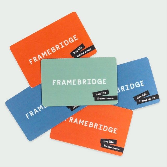 A set of orange, blue, and green Framebridge gift cards.