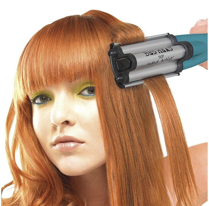 Model with red hair using a silver, blue, and black styling tool