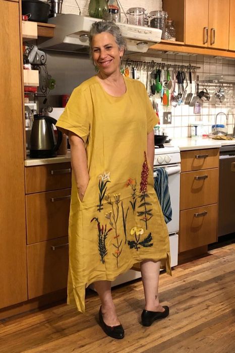 a reviewer modeling the embroidered midi dress in a sunny yellow shade