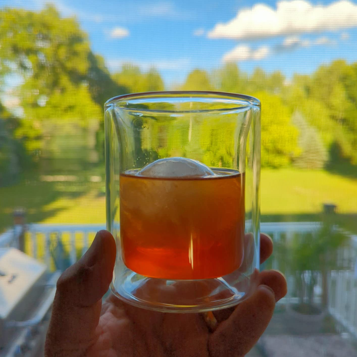 A reviewer holding one of the insulated glasses with a drink inside