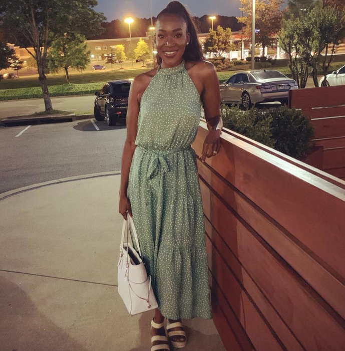 A reviewer wearing a green dress with a belt