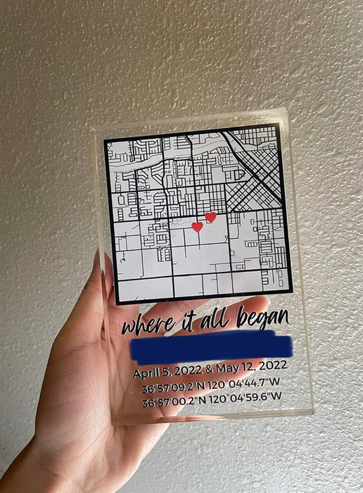 A person holding a custom plaque showcasing a map with two red heart markers and accompanying text