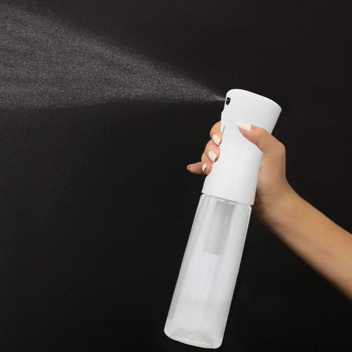 A model misting their hair with water from the white mister