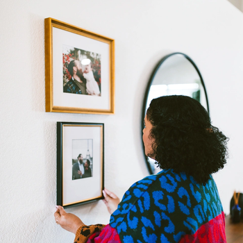 A model hanging a framed photo on the wall.