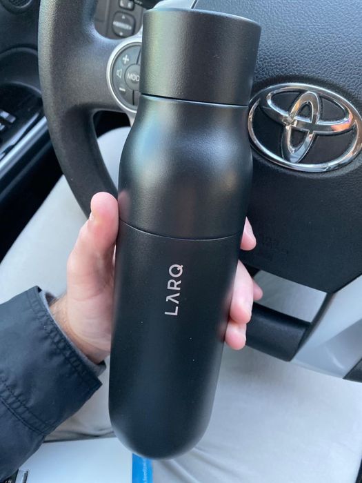 A reviewer holding the bottle in black