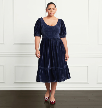A model showcasing the navy velvet dress.