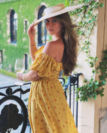 A reviewer in a yellow off-the-shoulder puff sleeve floral midi dress