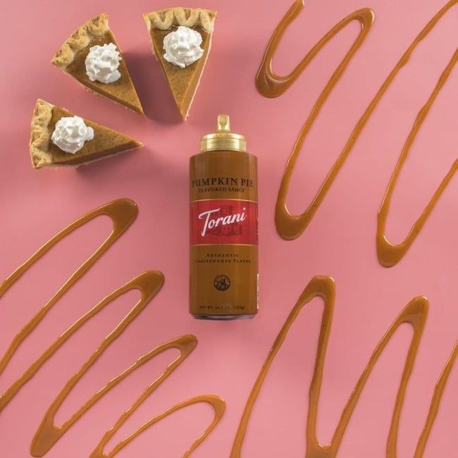 A bottle of Torani's Pumpkin Spice sauce placed next to slices of pumpkin pie.