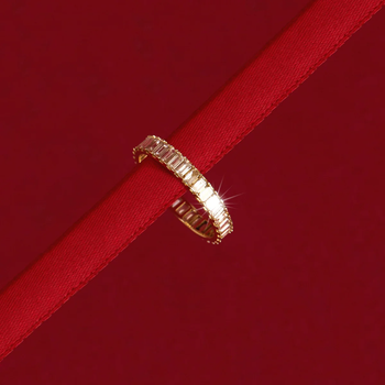 A close-up shot of a dazzling diamond ring placed on a red ribbon.