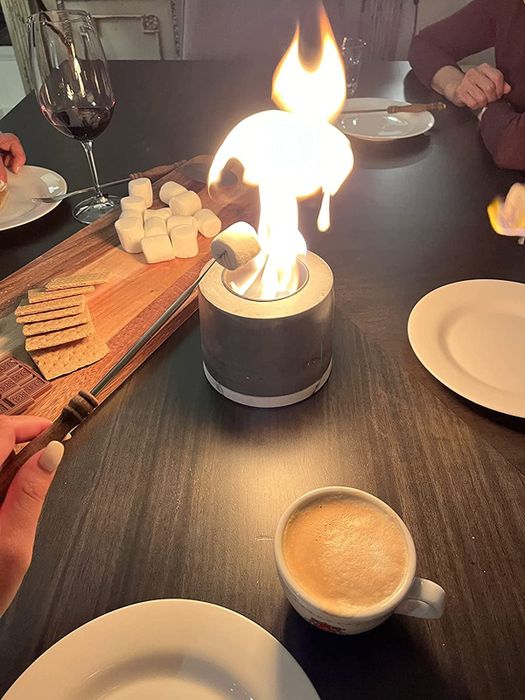 A reviewer roasting a marshmallow over a lit tabletop firepit.