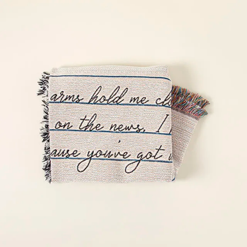 A blanket folded neatly with three lines of handwritten text displayed on the front