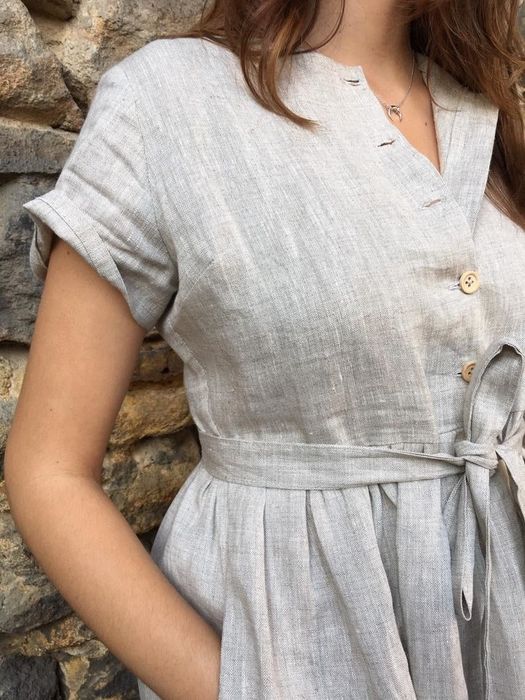 A close-up of the model's hands resting in the pockets, the short sleeves, and the button closures running down the front of the dress
