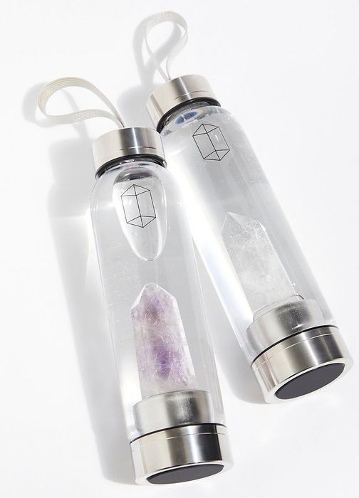 Two transparent water bottles with silver bottoms and caps, each containing crystals at the base.