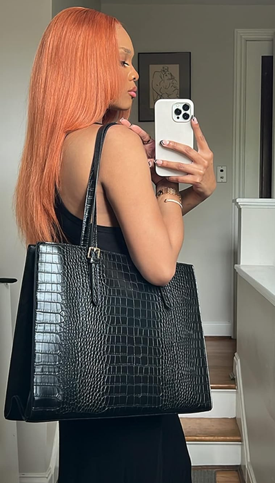 A reviewer showcasing a black laptop tote bag in use