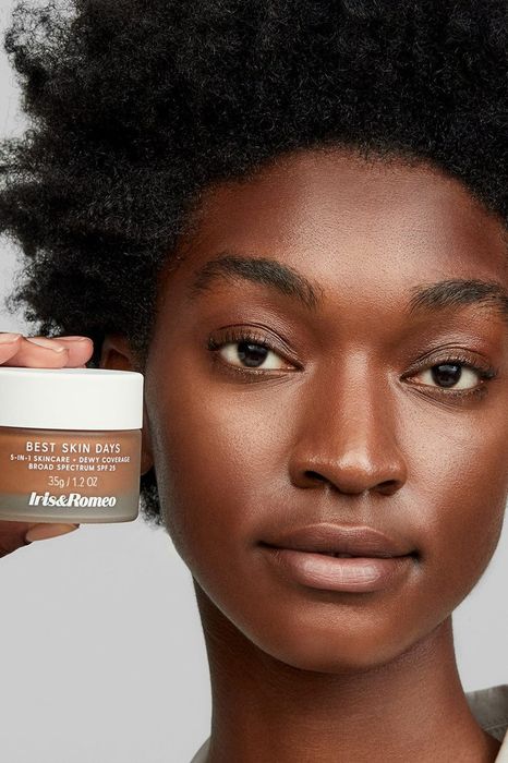 a model showcasing and holding the tinted moisturizer in shade 11
