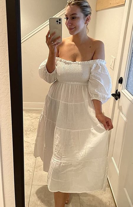 A reviewer flaunting the white dress with off-the-shoulder sleeves.