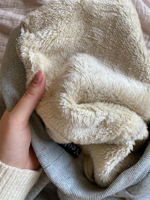 A reviewer revealing the soft sherpa lining on the inside.