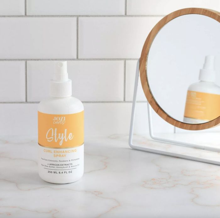 A bottle of curl spray and a mirror