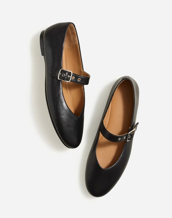 A pair of black Mary Jane shoes with buckles, positioned side by side on a white background