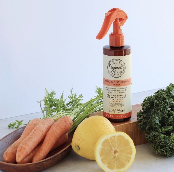 A bottle of braid spray with cut lemons and carrots