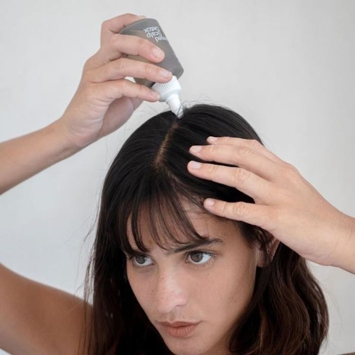 Model applies the scalp detox treatment directly to their scalp