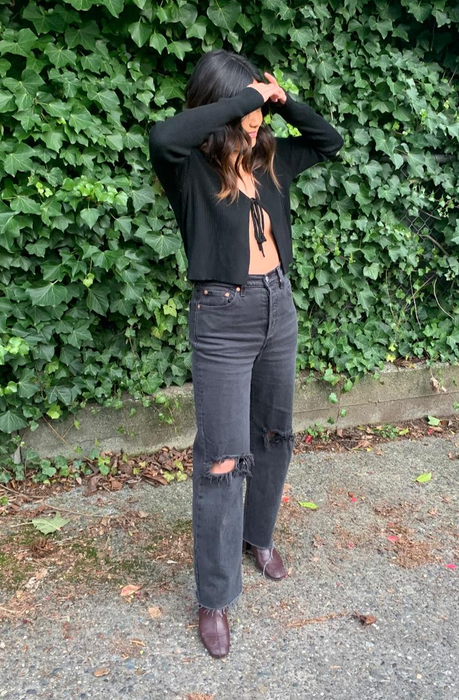 A reviewer styling the jeans in a distressed black finish.