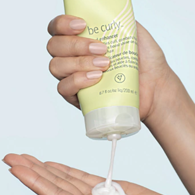 Hand squeezes a tube of the same curl enhancer