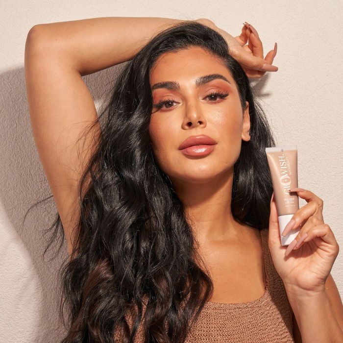 the founder of Huda Beauty holding a tube of the skin tint