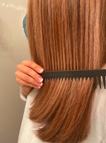 Reviewer uses a detangling comb to work through knots in their reddish-brown hair