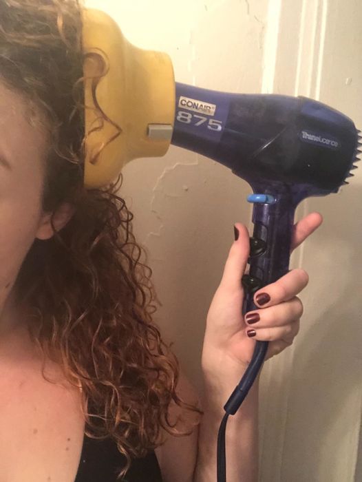 Reviewer applies the same diffuser to their blow dryer to dry their curly locks