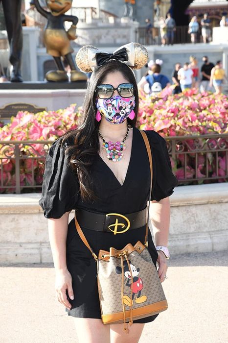 A customer styling a black dress with a bold Disney belt featuring a thick black strap and a prominent 'D' buckle.