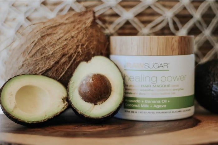 A jar of nourishing hair mask paired with a sliced avocado and coconut