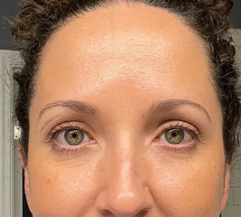 A reviewer with a shiny forehead showing the effects of makeup.
