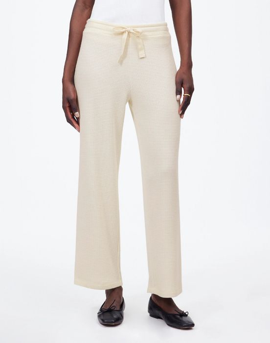 Person wearing cream-colored knit sweatpants with a drawstring waist, paired with black ballet flats for a chic yet relaxed look.