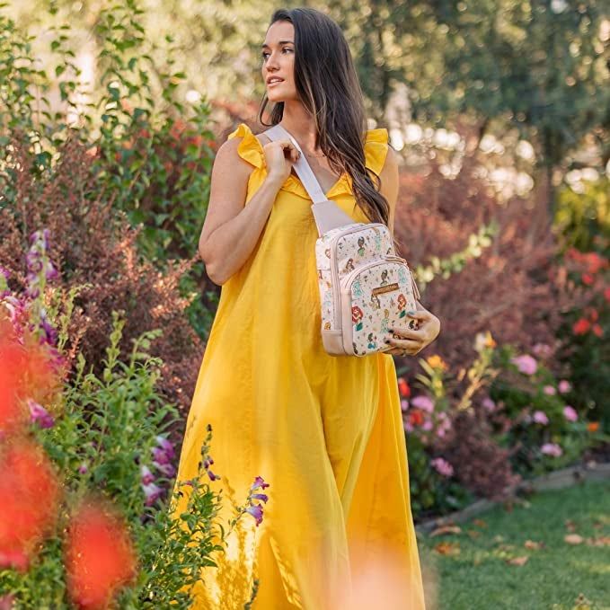a model holding a sling bag covered in princess designs