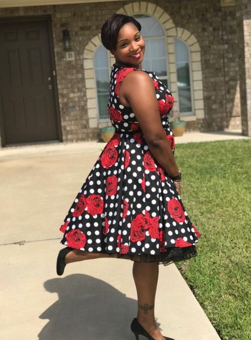 Reviewer showcasing a sleeveless dress with a red floral and polka dot design.
