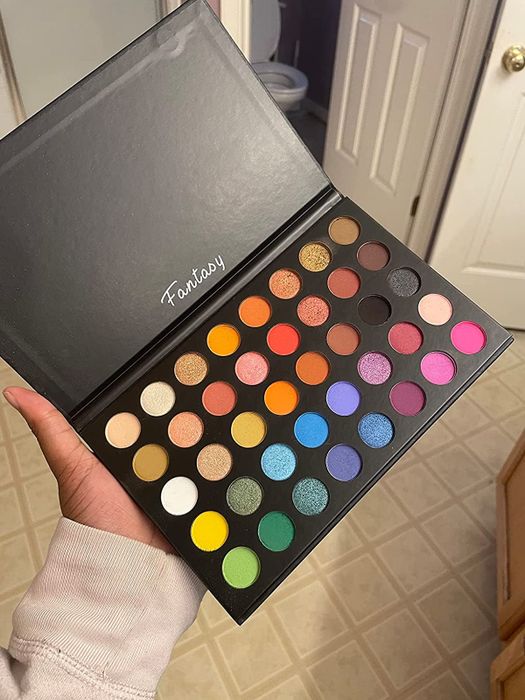 A hand holding the vibrant 40-shade rainbow eyeshadow palette