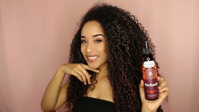 Model holding the bottle of Defunk Hair Odor Neutralizing Tonic
