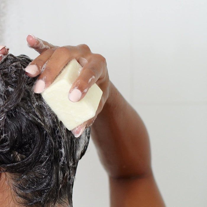Model uses the Ethique shampoo bar to lather their hair in the shower
