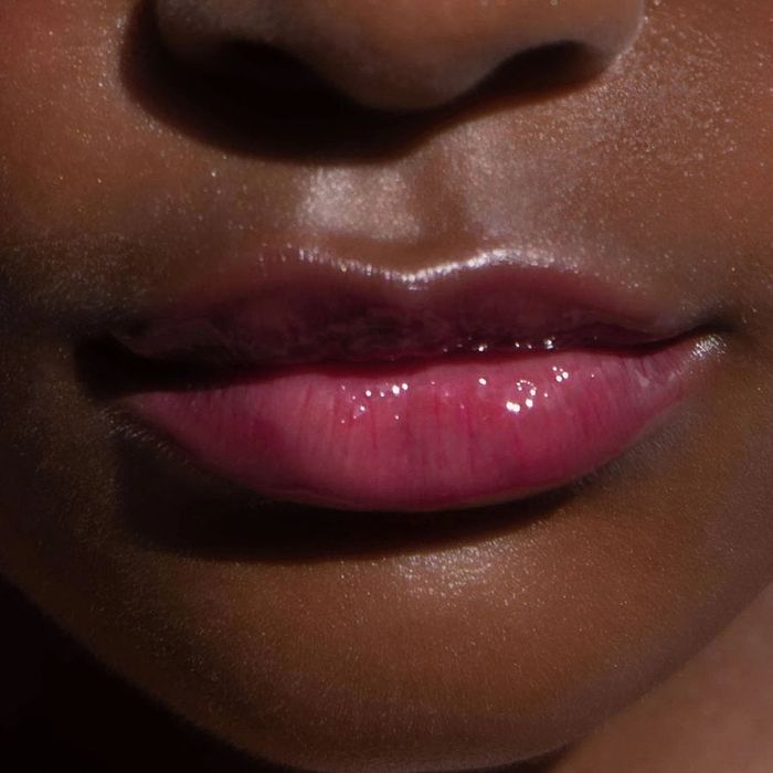 A close-up shot of a model wearing the bright, ultra-pigmented pink lip gloss.