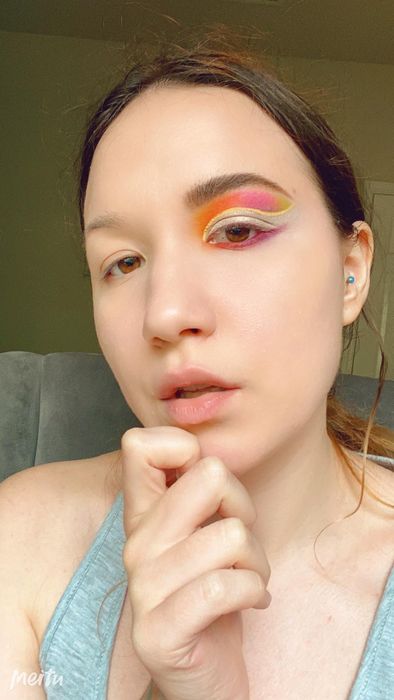A reviewer's eye makeup featuring orange, pink, and yellow shades from the palette